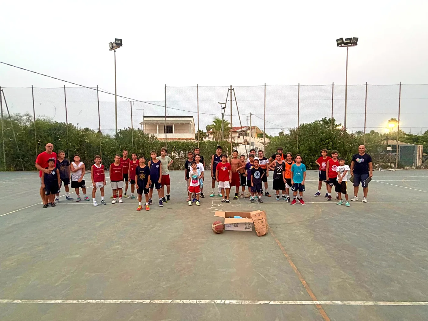 I ragazzi del torneo e gli organizzatori schierati a centrocampo sul campo di Caucana, al tramonto.