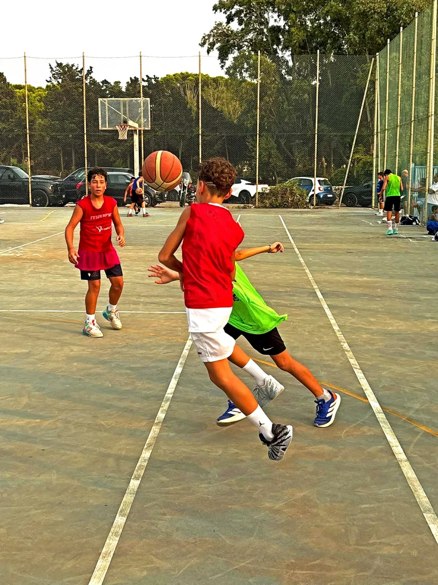 Un passaggio in corsa, con il pallone a mezz'aria fra due giocatori in maglia rossa.